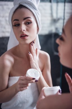 Güzel kız banyo havlusu banyo aynada içine bakarken krem boynunda ayırıyor