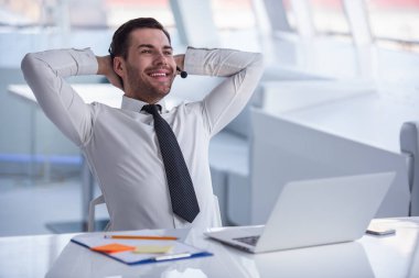 Takım elbise ve kulaklık yakışıklı işadamı laptop Office ile çalışırken gülümsüyor