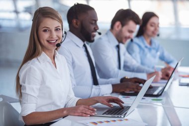 Çekici iş adamları takım elbise ve kulaklık dizüstü bilgisayarlar Office ile çalışırken gülüyorsun