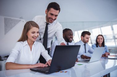 Çekici iş adamları takım elbise ve kulaklık dizüstü bilgisayarlar Office ile çalışırken gülüyorsun