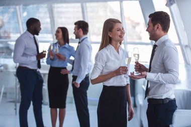 Başarılı iş adamları şampanya içmek, konuşmak ve ofiste süre kutlama gülümseyen