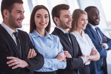 Güzel iş takım resmi elbiseli Office çapraz silah ile üst üste duran gülümseyerek. Kız kameraya bakıyor