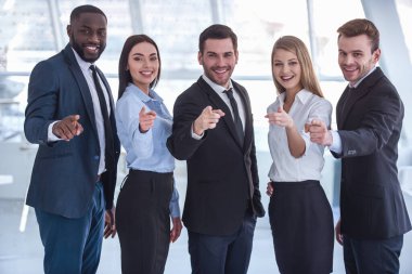 Güzel iş resmi elbiseli gülümseyen, seyir ve kamera Office dururken işaret