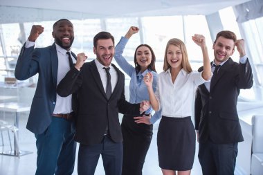 Güzel iş takım resmi elbiseli kameraya bakarak ve Office dururken gülümseyen yumruk, elinde yetiştirme