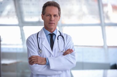 Yakışıklı olgun doktor duran katlanmış silah ile kamera bakıyor