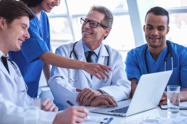 Başarılı tıp doktorları bir dizüstü bilgisayar kullanarak ve bir tartışma yaparken gülümseyen