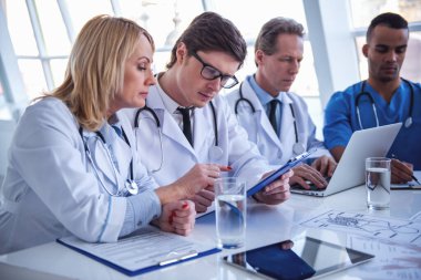 Başarılı tıp doktorları bir dizüstü bilgisayar kullanarak ve belgeleri konferans sırasında tartışıyor