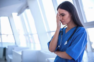 Mavi önlük içinde güzel doktor hastane koridorda duran yüzünü kaplayan