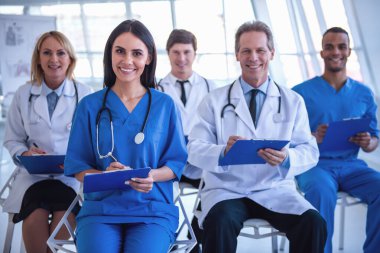 Başarılı tıp doktorları notlar, kameraya bakıyor ve süre toplantısında gülümseyen