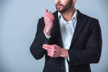 Kol düğmesi gri arka plan üzerinde ayarlama takım elbiseli yakışıklı işadamı kırpılmış görüntü