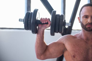 Çıplak gövde dumbbells ile dışarı çalışırken kameraya bakarak ile yakışıklı kaslı adam Resim kırpılmış