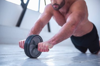 Çıplak gövde egzersiz tekerlek ile çalışma dışarı ile yakışıklı kaslı adam Resim kırpılmış