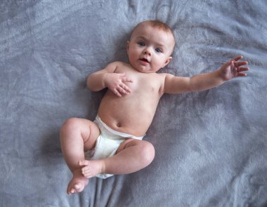 Yatakta yatarken kameraya bakarak büyük mavi gözlü şirin bebek portresi
