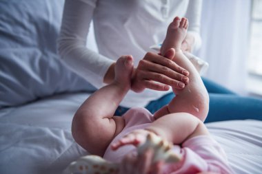 Genç anne onun bebek ihale cilt üzerinde krem uygulayarak Resim kırpılmış