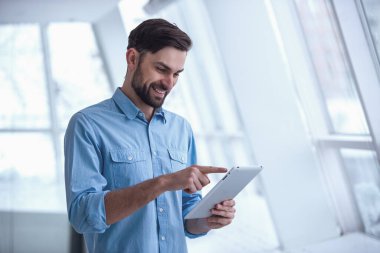 Yakışıklı işadamı dijital tablet kullanma ve Office dururken gülümseyen