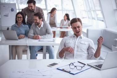 İş adamları becerikli, söz ve ofiste çalışırken gülümseyen kullanıyorsunuz. Adam ön planda müzik ve gitar taklit