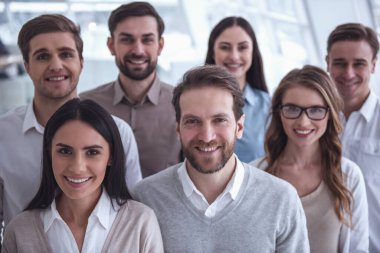 Güzel iş takım kameraya bakarak ve Office dururken gülümseyen