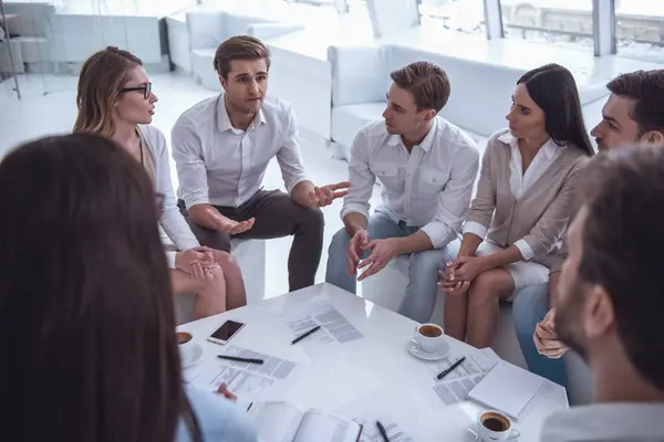 Business people are discussing affairs while sitting in circle in office