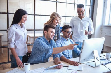 Güzel iş adamları bilgisayarları kullanan ve ofiste çalışırken gülümseyen