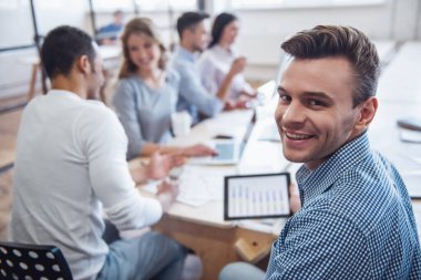 Güzel iş adamları ofis konferansı boyunca aletler kullanıyor, konuşuyor ve gülümsüyor.