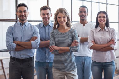 Başarılı iş takım kameraya bakarak ve Office çapraz kolları olan dururken gülümseyen