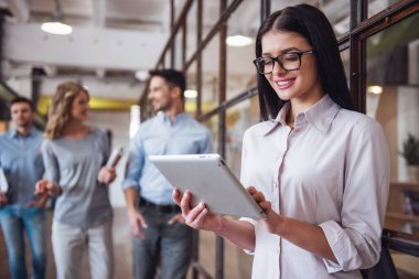 Güzel iş kadını dijital tablet kullanma ve Office dururken gülümseyen