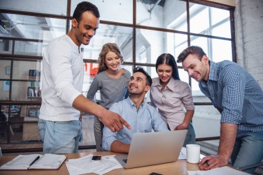 Güzel iş adamları konuşuyor ve Office toplantısında gülümseyen bir dizüstü bilgisayar kullanıyorsanız