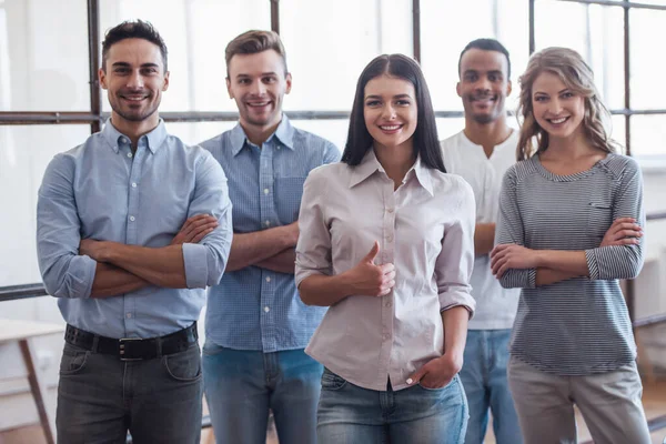 Başarılı iş takım kameraya bakarak ve Office çapraz kolları olan dururken gülümseyen