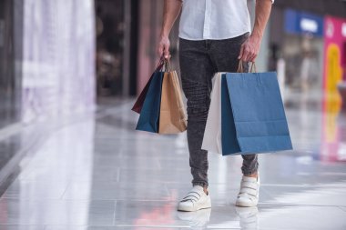 Alışveriş merkezinden alışveriş yapan, alışveriş çantalı yakışıklı bir adam görüntüsü.