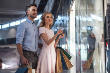 Güzel çift alışveriş torbaları ile konuşmak ve çarşıda alışveriş yaparken gülümseyen