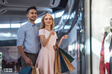Güzel çift alışveriş torbaları ile konuşmak ve çarşıda alışveriş yaparken gülümseyen