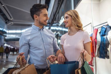 Güzel çift alışveriş torbaları ile konuşmak ve çarşıda alışveriş yaparken gülümseyen