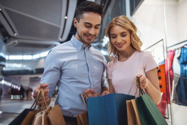 Güzel çift alışveriş torbaları ile konuşmak ve çarşıda alışveriş yaparken gülümseyen