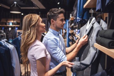 Güzel çift resmi takım seçme ve erkek mağazada alışveriş yaparken gülümseyen