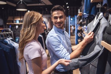 Güzel çift resmi takım seçme ve erkek mağazada alışveriş yaparken gülümseyen