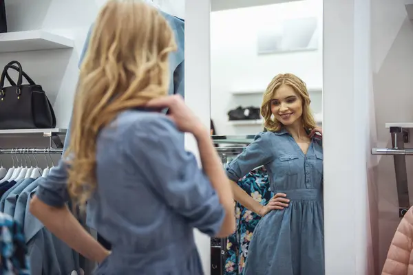 美しい若い女性がドレスを選択してショッピング モールでのショッピングをしながら笑みを浮かべて — ストック写真