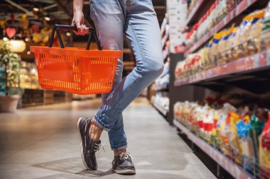Süpermarkette alışveriş yaparken bir Pazar sepeti ile yakışıklı adamın kırpılmış görüntü