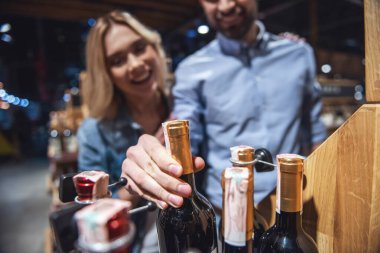 Güzel genç çift konuşmak ve şarap süpermarkette seçerken gülümseyen