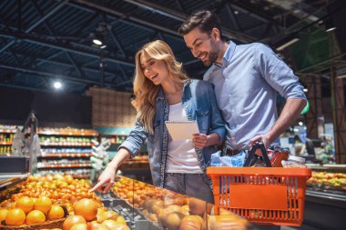 Güzel çift süpermarkette alışveriş yaparken gülümsüyor