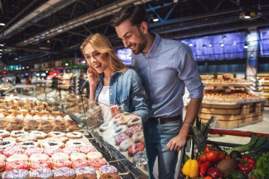 Güzel çift seçerek pişirme ve süpermarkette alışveriş yaparken gülümseyen