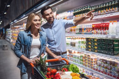 Güzel çift konuşmak ve süpermarkette alışveriş yaparken gülümseyen