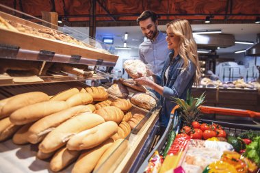 Güzel genç çift seçerek pişirme ve süpermarkette alışveriş yaparken gülümseyen