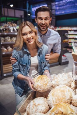 Güzel genç çift seçerek pişirme ve süpermarkette alışveriş yaparken gülümseyen