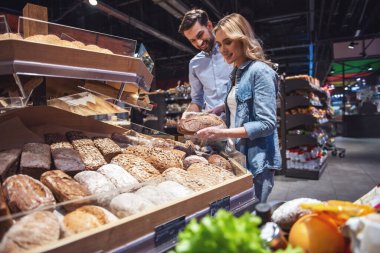 Güzel genç çift seçerek pişirme ve süpermarkette alışveriş yaparken gülümseyen