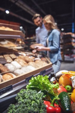 Güzel genç çift seçerek pişirme ve süpermarkette alışveriş yaparken gülümseyerek. Odak gıda
