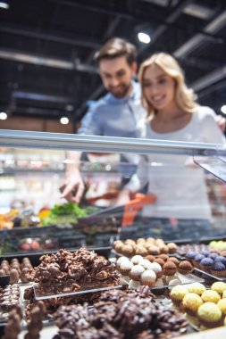 Güzel genç çift süpermarkette alışveriş yaparken gülümsüyor