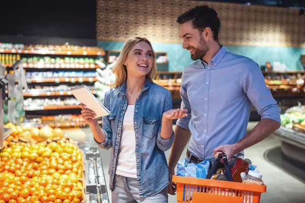 Güzel çift konuşmak ve süpermarkette alışveriş yaparken gülümseyen