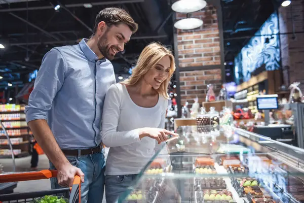 stock image Beautiful young couple is smiling while doing shopping at the supermarket