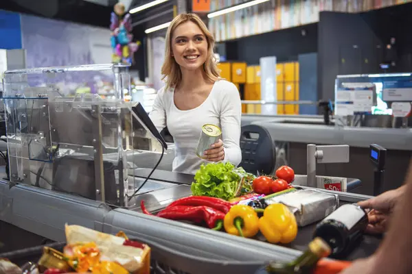 Güzel genç kasiyer markette çalışırken gülümsüyor