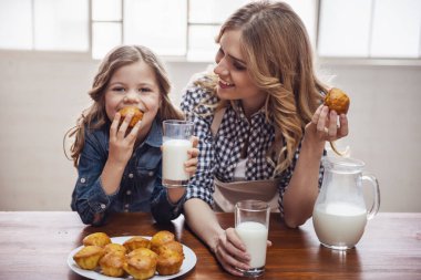 Sevimli küçük kız ve onun güzel genç anne sütlü kek yeme ve evde istirahat ederken gülümseyen